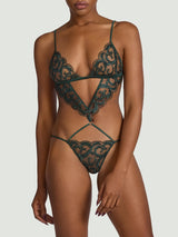 Model showing the front of a Coco de Mer lingerie playsuit. Made from a dark green floral embroidery on a sheer tulle with silk straps.