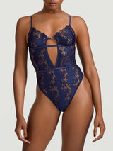 A deep navy blue bodysuit with white floral embroidery, designed with a soft cup shape, silk bands, and a teardrop cut-out at the chest as shown on model