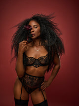 Dame Denise Lewis wears a black Coco de Mer Hera Balcony Bra made with intricate Leaver's lace detailing, and matching Hera Suspender Belt and Brazilian Knicker