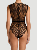 A black scalloped Leaver's lace bodysuit with a boat neckline, eyelash trim, and velvet buttons down the spine, designed in London and made in Portugal.