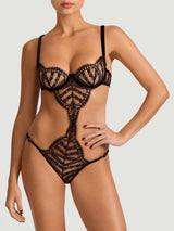 An intricate black French Leaver's lace playsuit with velvet accents, featuring a plunge bra shape, open crotch, and adjustable straps shown on model