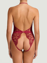 A red lurex Leaver's lace playsuit with a halterneck shape, delicate eyelash trim at the bust, and a silk band at the waist. It includes an open bottom, sleek adjustable silk straps and delicate golden hardware.