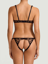 An intricate black French Leaver's lace playsuit with velvet accents, featuring a plunge bra shape, open crotch, and adjustable straps as shown on model