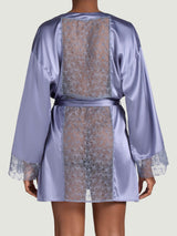 Model showing the back of the Esme Coco de Mer silk robe in powder blue. There is a sheer insert of geometric floral embroidery throughout the back.