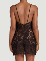 The back view of a model wearing the Coco de Mer Aphrodite slip. Made from a black, sheer French Leavers lace with a delicate eyelash edge along the neck and hemlines. Also featuring a side split and delicate thin straps.