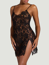 The front view of a model wearing the Coco de Mer Aphrodite slip. Made from a black, sheer French Leavers lace with a delicate eyelash edge along the neck and hemlines. Also featuring a side split and delicate thin straps.