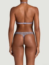 Model showing the back of a Coco de Mer Esme lingerie set. Soft cup halter bra and skirted thong in powder blue. Bespoke geometric floral embroidery and silk