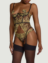 Model wears a UK size M black underwire quarter cup basque with gold embroidery and silk suspender straps attached to sheer black suspenders, paired with black open knickers with gold embroidery