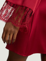 A close up of the red French leaver's lace of the Coco de Mer Renata Robe. At the end of the sleeve meets a red delicate scallop edge lace that sits just above the knuckles. This pairs perfectly with the red silk.