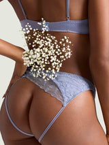 Model showing the back detials of the Coco de Mer Esme lingerie set. The quarter cup bra and open knickers are made of powder blue silk and geometric floral embriodery.
