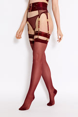Side image of model wearing morello waist cincher, gold sliders attached to adjustable suspender straps and across the front, with a central gold zip across the whole piece. Mesh suspenders attached by gold rings, paired with morello hold ups