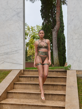 Model wears a UK size M in the Olive multiway bodice, with mesh cups underneath adjustable harness straps, gold sliders across each strap going above the chest and following up to the neck, paired with the Olive harness brief from the front
