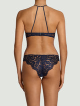 Model wears a UK size M in the tamara high neck plunge bra from the back, sapphire lace underband attached to silk straps, paired with the tamara sapphire lace scallop edge brazilian knicker from the back worn in a UK size M.