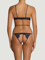 Model wears a UK size M in wired open playsuit from the back, showing exposed bottom with scallop edge sapphire lace detailing across the back and silk straps across the waist