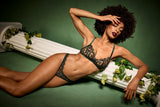 Coco de Mer lingerie campaign image. Model wearing a dark green floral embriodered lingerie set, with a soft cup bra, V front thong and scalloped edges. 