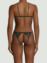Model showing the back of a Coco de Mer open playsuit with dark green floral embroidery and silk strapping. 