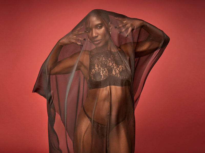 Dame Denise Lewis wearing Coco de Mer's Hera High Neck Balconette Bra made in a luxurious black Leaver's lace with scalloped edges and a quarter cup design for support. Paired with matching Hera Brazilian Knicker