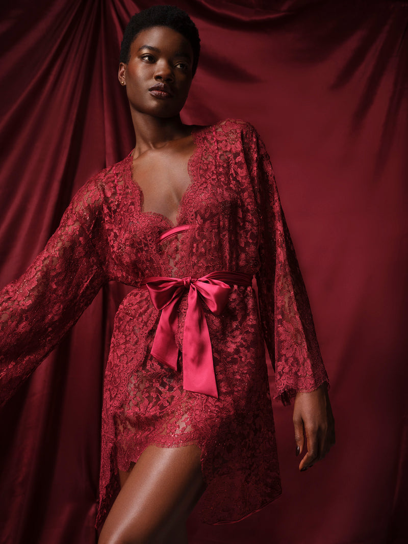 A red lurex leaver's lace robe with a silk belt, designed with wide sleeves and scalloped edges at the neckline and cuffs, paired with matching slip as shown on model