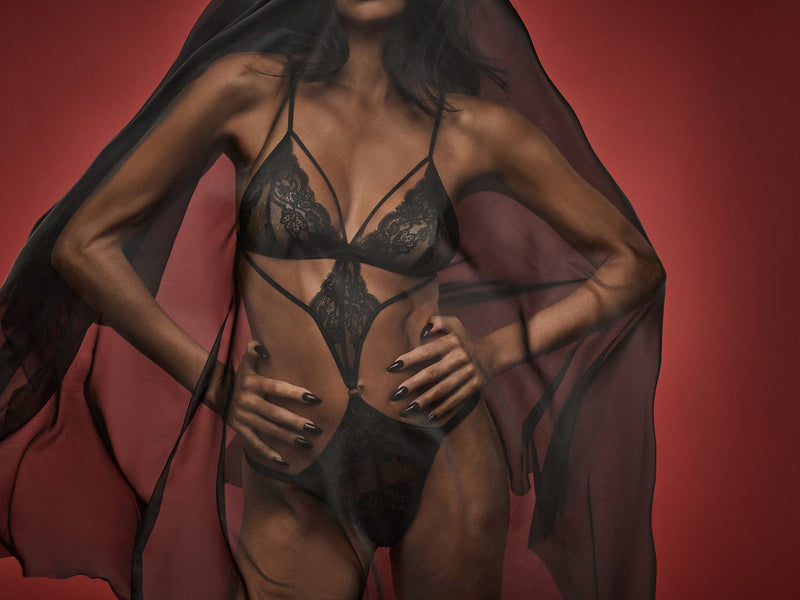 Dame Denise Lewis wears an elegant Seraphine black open playsuit with intricate Leaver's lace detailing and silk shoulder straps.
