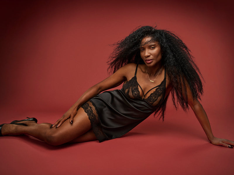 Dame Denise Lewis wears a black Coco de Mer Seraphine silk slip dress with French Leaver's lace detailing, featuring slim straps and a triangle lace cup design.