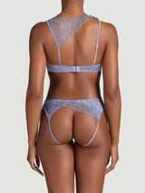 Model showing the back view of the Coco de Mer Esme lingerie set. Powder blue silk and sheer floral embroidery in an asymmetric silhouette. Quarter cup bra and open knicker. 