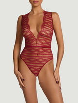 A model wearing a red scalloped Leaver's lace bodysuit with a plunging scallop edge neckline, eyelash trim, and a red silk waistband, designed in London and made in Portugal.