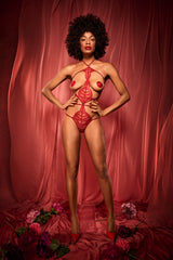 A model wearing an intricate red French leavers lace open playsuit, featuring open cups, an open crotch and adjustable silk binding strapping.