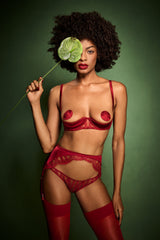 A model wearing an intricate red French Leaver's lace and luxurious silk suspender knicker with a high waist and adjustable straps, featuring golden hardware and scallop edge lace details. This is paired with a red quarter cup bra featuring details of scallop edged Leaver's Lace lining a silk covered quarter cup and silk straps with a hook and eye closure at the spine.