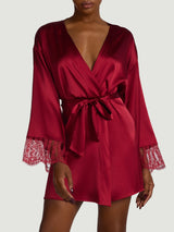 A model wearing a red silk robe with red scallop edged French leaver's lace down the centre back and along the cuffs of the sleeve with a red silk tie at the waist.