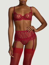 A model wearing a red French Leavers lace suspender belt featuring a scalloped edge along the bottom and a red silk waistband at the top. There are two suspender clips at both the front and the back in the centre of each leg.