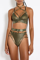 Front image of model wearing a UK size M in the harness brief with mesh knicker underneath, small gold sliders attached to adjustable straps across the front with a thick waist band and gold ring detailing centrally on the front paired with the multiway bodice in olive