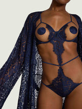 Model wears a UK size M in the underwire open playsuit with scallop edge sapphire lace detailing across the body with silk straps across the waist, legs and shoulders, paired with the sapphire lace robe 