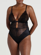 A black Coco de Mer Athena Bodysuit with graphic embroidery and a deep plunging neckline. It includes fan edged cups, an underbust band of jet black silk, adjustable silk straps, and gold hook and loop fastenings